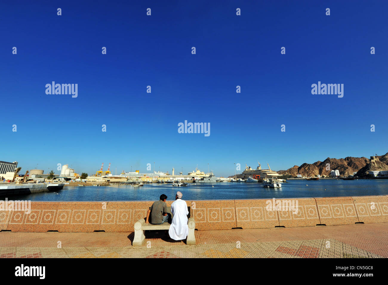 Sultanat d'Oman, Muscat, Muttrah zone portuaire, Omani men assis sur un banc public sur la Corniche Banque D'Images