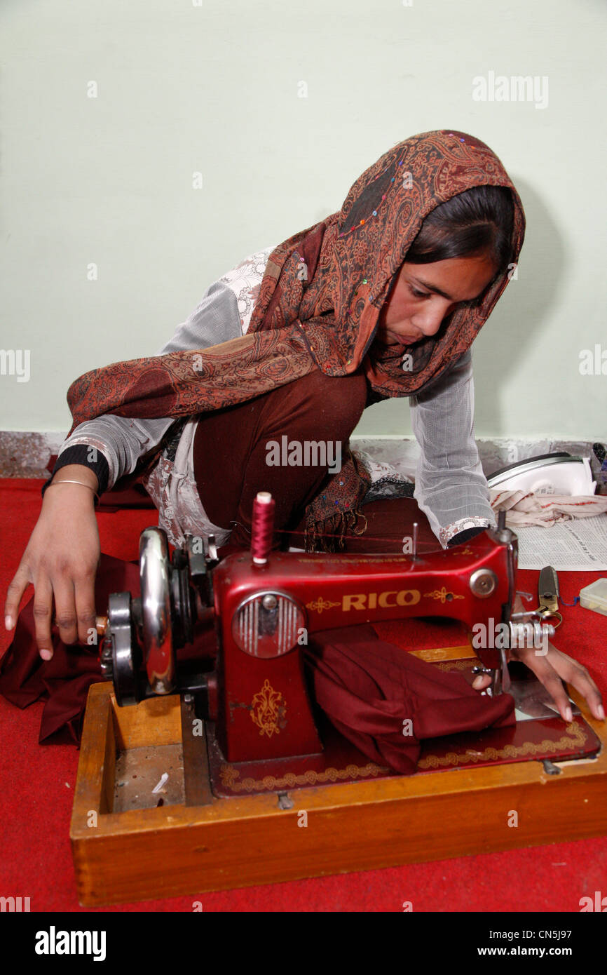 Dehradun, Inde. Femme musulmane indienne travaillant avec le manuel d'instructions de couture machine à coudre dans la classe. Banque D'Images