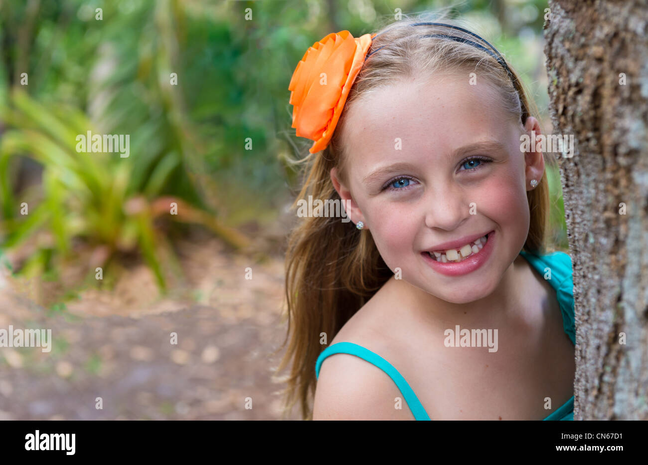 8 ans caucasian girl derrière un arbre dans un jardin. Banque D'Images