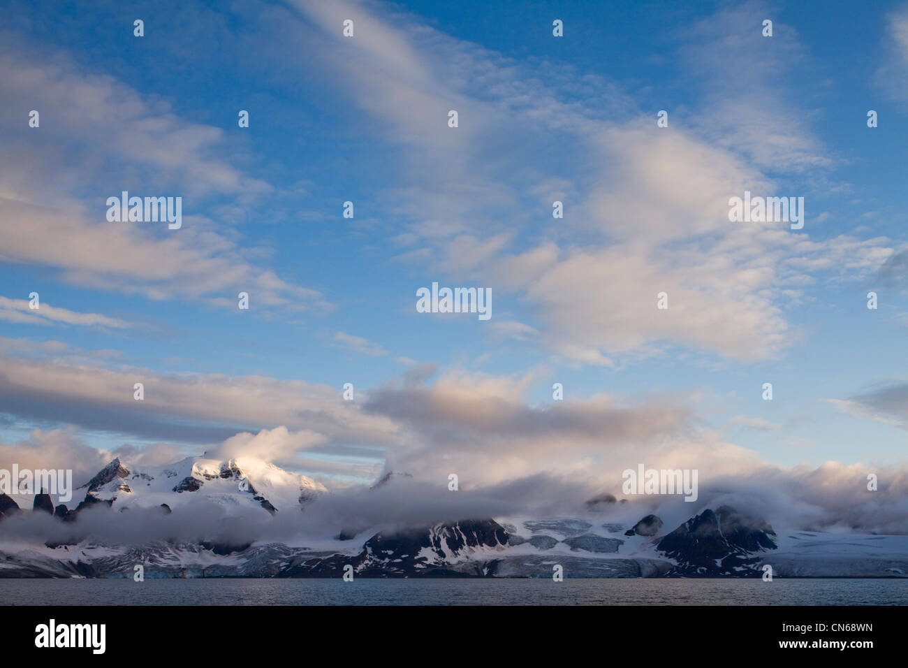 La Norvège, Svalbard, Spitzberg, Coucher de soleil nuages au-dessus de feux de montagnes couvertes de glaciers sur Prins Karls Forland Island Banque D'Images