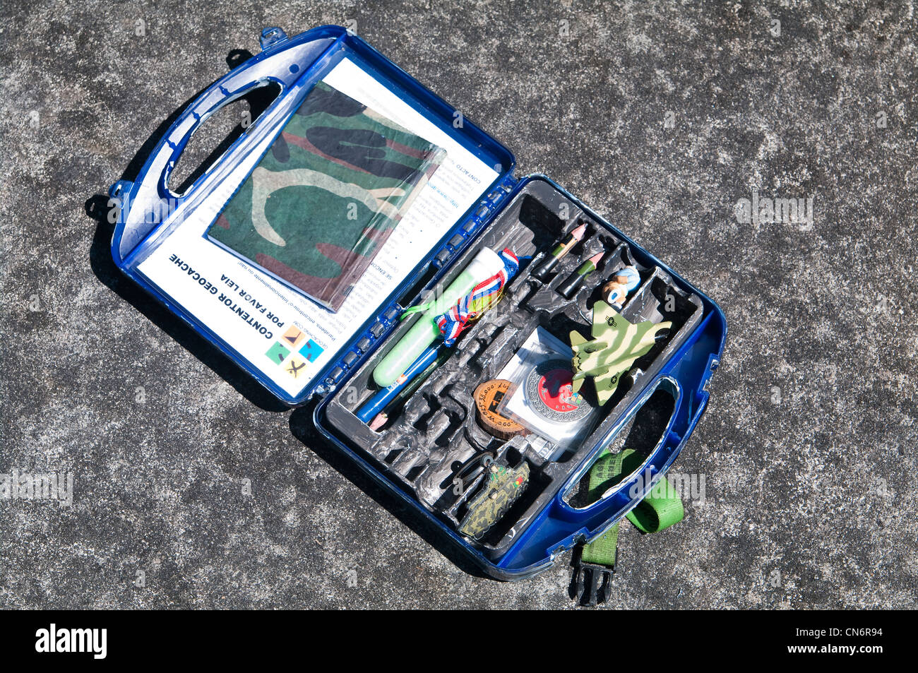 Conteneur de chasse au trésor ouvert rempli de bibelots, de jouets et d'un journal de bord, trouvé lors d'une chasse au trésor aux Açores, au Portugal. Banque D'Images