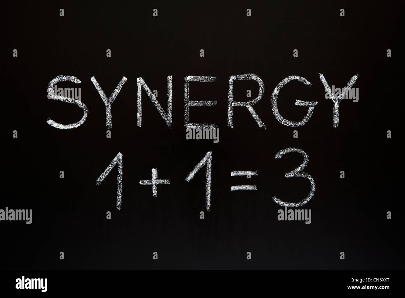 Synergie concept 1 +1 =3 faites avec craie blanche sur un tableau noir. Banque D'Images