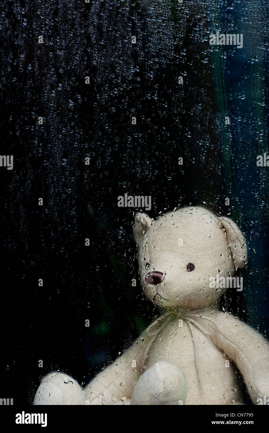 Triste ours à travers une fenêtre couverte de gouttes de pluie. Still Life Banque D'Images