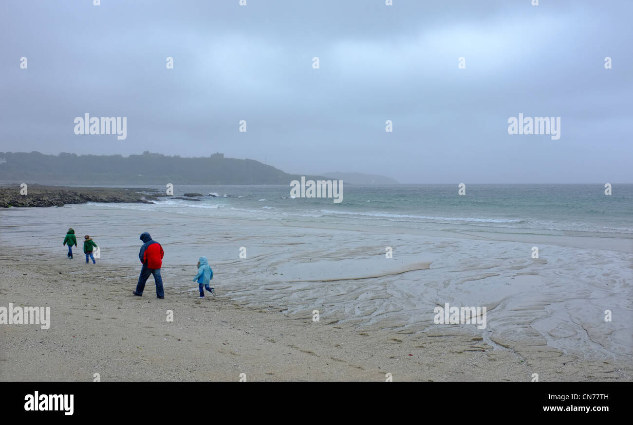 Une famille sur la plage Gyllyngvase à Cornwall à l'état humide et venteux jour Banque D'Images