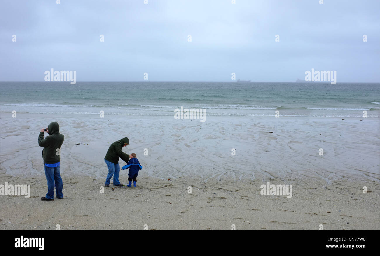 Une famille sur la plage Gyllyngvase à Cornwall à l'état humide et venteux jour Banque D'Images