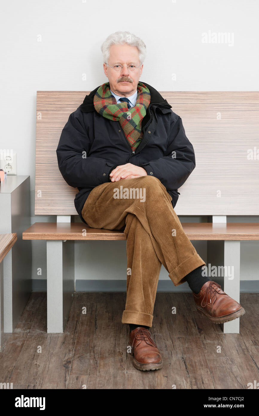 Un homme âgé, patiemment assis dans la salle d'attente d'une pratique médicale, attend son tour Banque D'Images