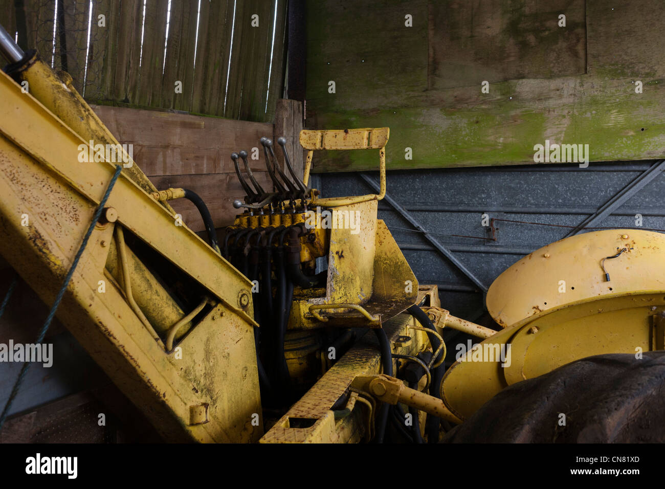 Tracteur jaune stocké dans un hangar couvert petite exploitation au printemps avant une autre année de l'utilisation. Banque D'Images