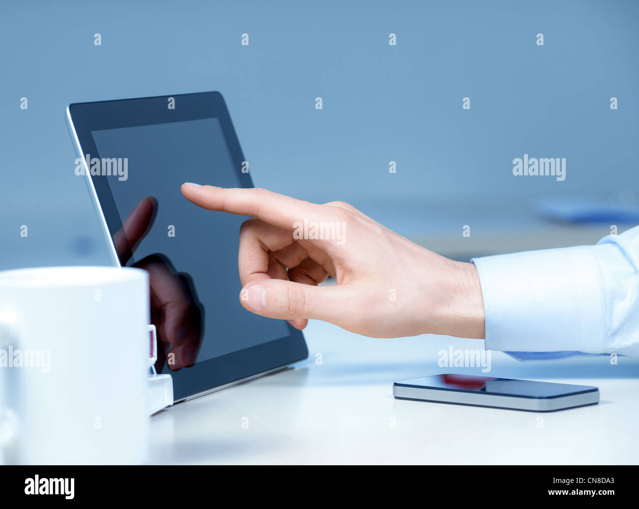 Main pointant sur le PC tablette numérique moderne sur le lieu de travail. Banque D'Images