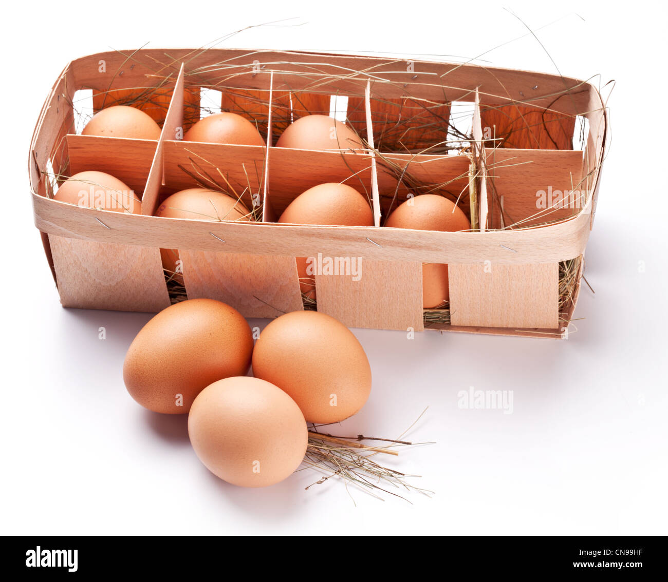 Les œufs avec une paille dans un panier en bois sur un fond blanc. Banque D'Images