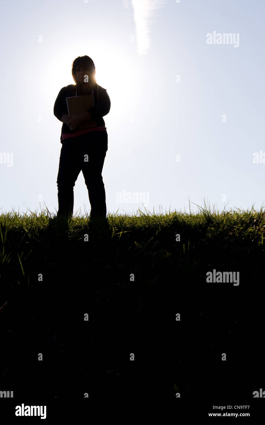 Silhouette d'une femme debout dans un champ éclairé Banque D'Images