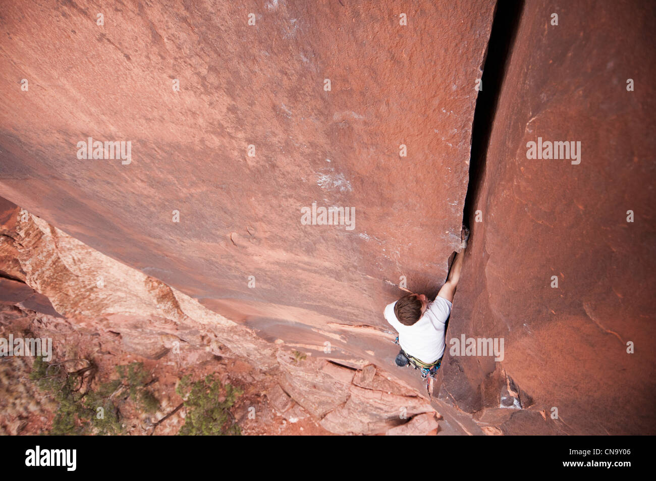 Rock climber scaling boulder crack Banque D'Images