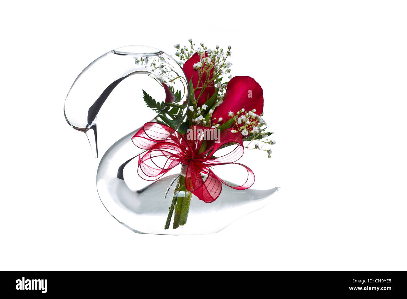 Cygne en verre avec des roses rouges, de petites fleurs blanches sur fond blanc Banque D'Images