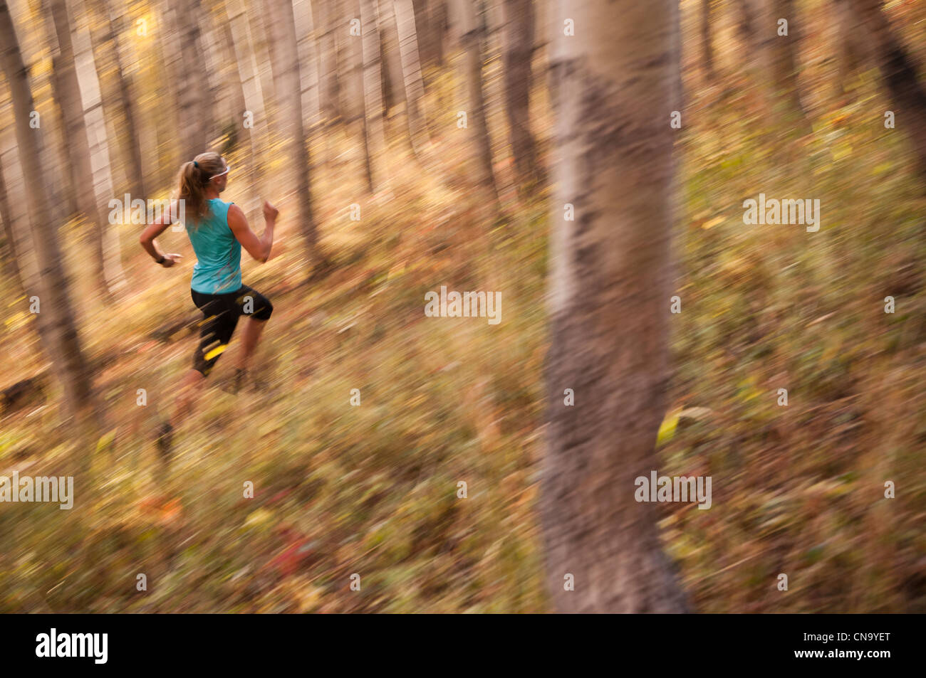 Blurred view of woman running in forest Banque D'Images