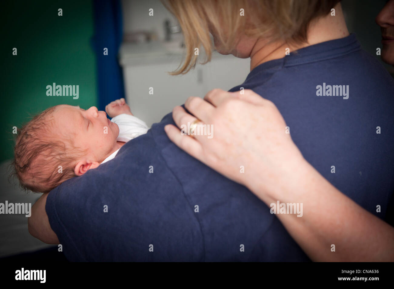 Une infirmière met une main réconfortante sur l'épaule comme une mère elle berceaux ici new born baby UK Banque D'Images