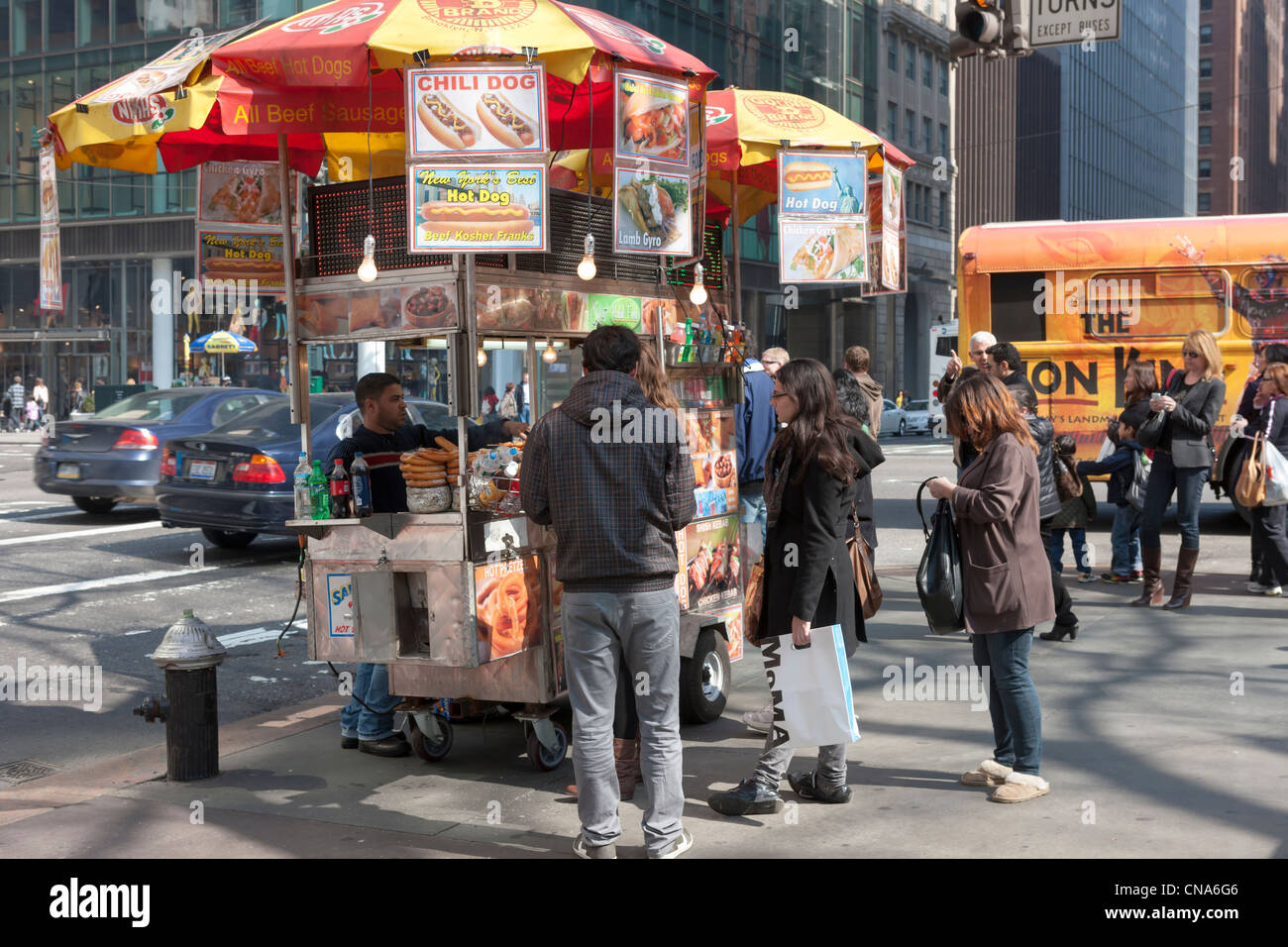Un vendeur de rue panier vente de hot-dogs et autres food travaille l'angle de la 5e Avenue et 42e Rue, dans la ville de New York. Banque D'Images