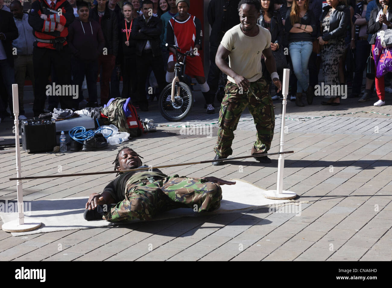 Des artistes de rue danse limbo sous un poteau avec un public d'observer les gens dans le centre-ville de Leeds Yorkshire Angleterre UK Banque D'Images