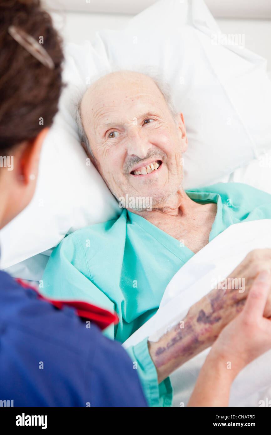 Un homme âgé patient être réconforté par une infirmière UK Banque D'Images
