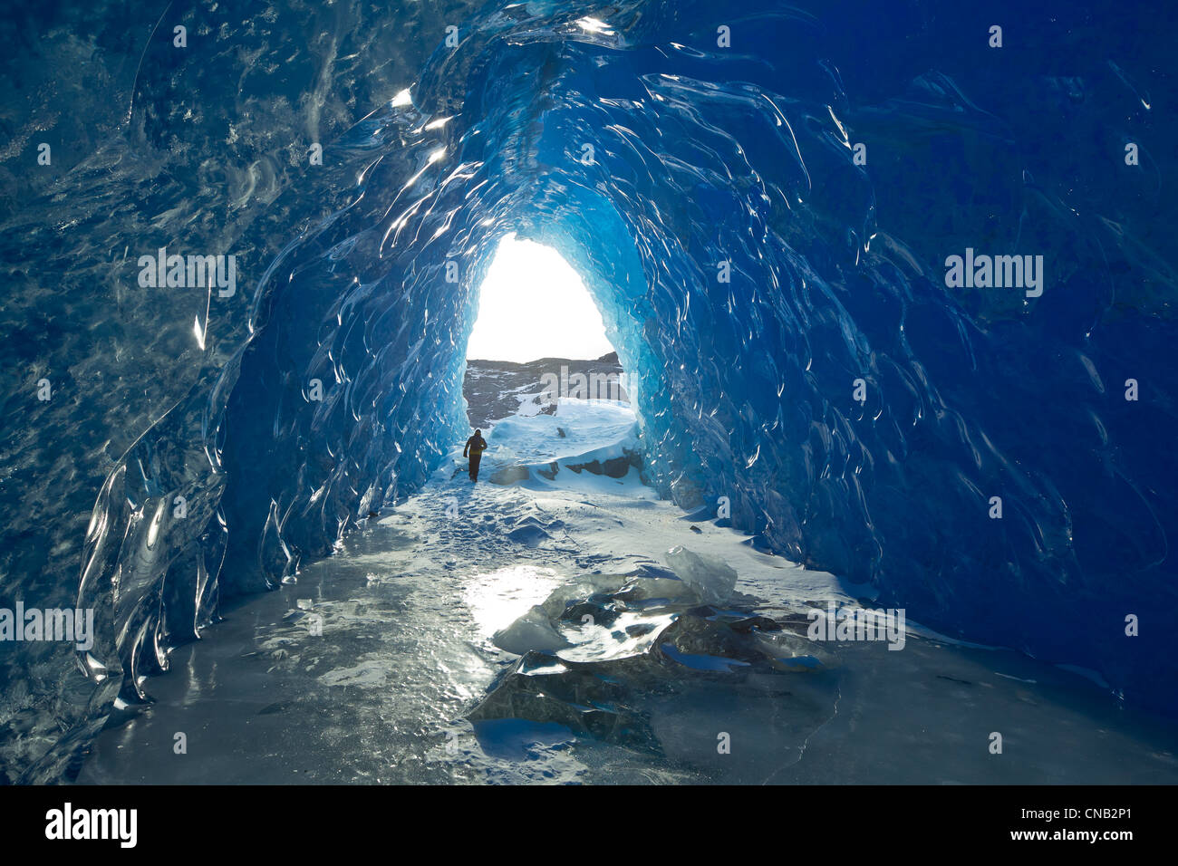 Homme marche à l'intérieur d'une grotte de glace d'un iceberg dans le lac gelé de Mendenhall, Juneau, Alaska du Sud-Est, l'hiver Banque D'Images