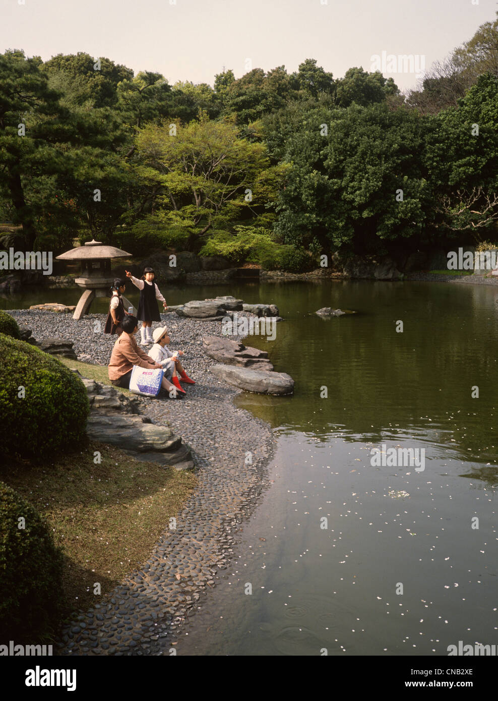 Jardin du Palais Impérial de Tokyo Japon lac ornemental avec lanterne et de la famille par l'eau Banque D'Images