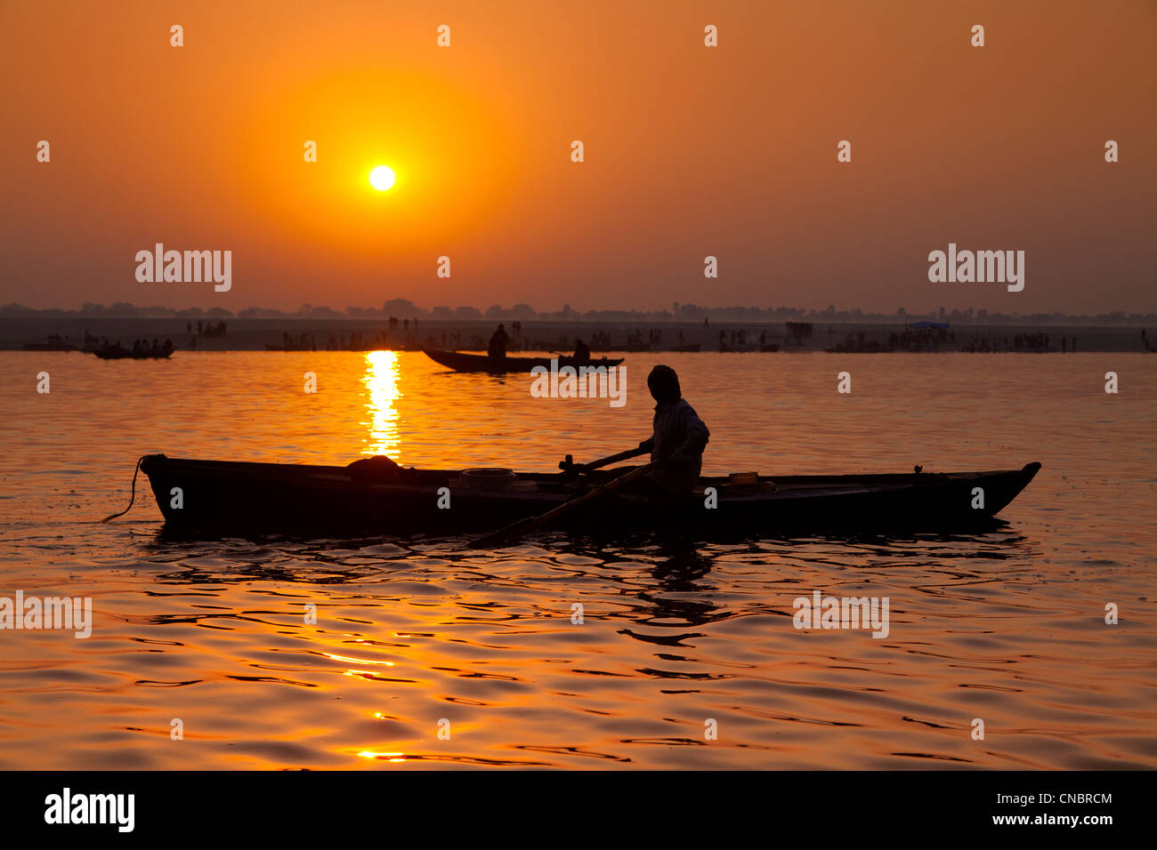 L'Inde, Uttar Pradesh, Varanasi, le lever du soleil sur le Gange avec batelier en premier plan Banque D'Images