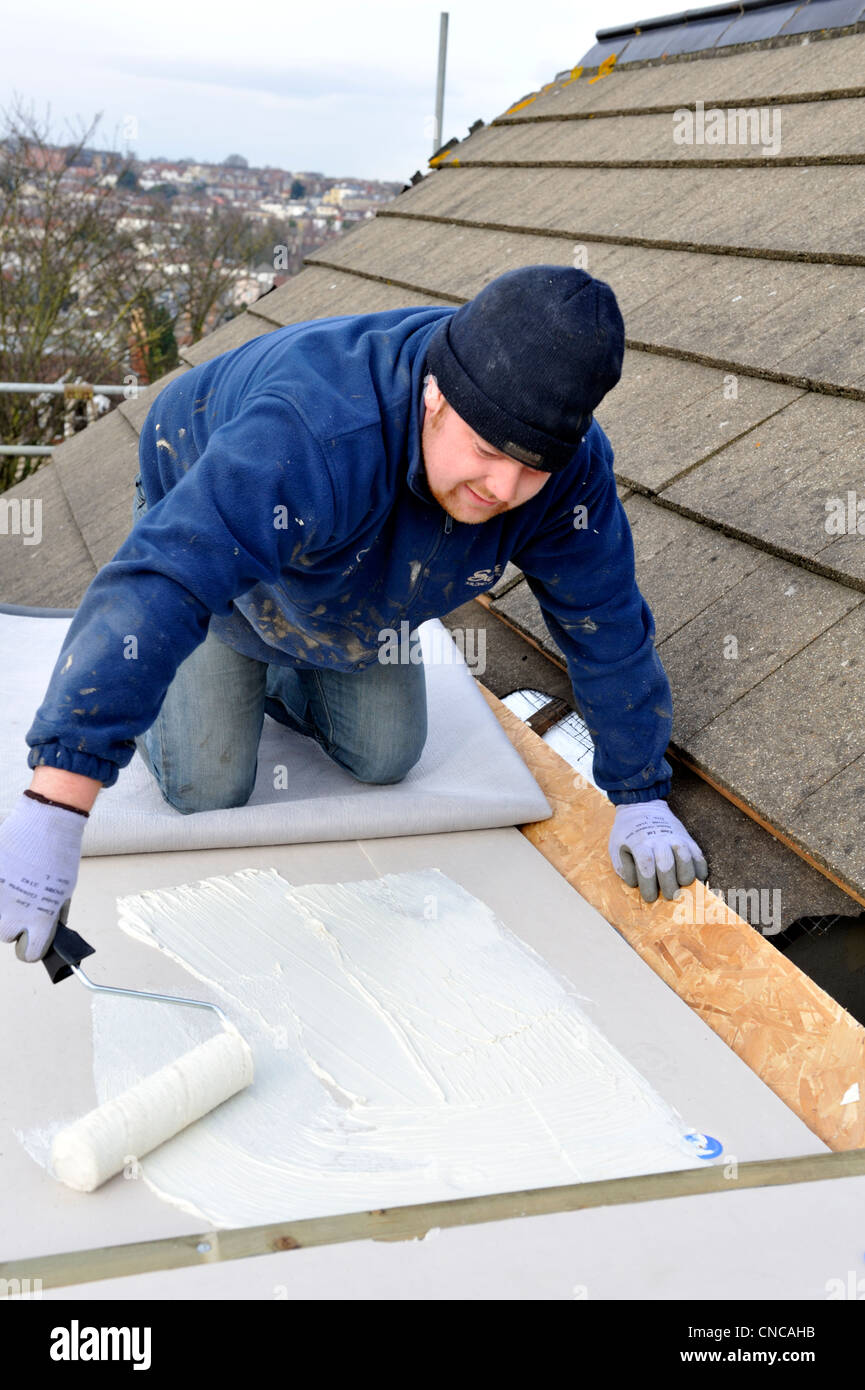 L'adhésif sur la propagation couvreur conseil d'isolation toiture plate à installer de nouvelles membranes en caoutchouc EPDM sur house Banque D'Images