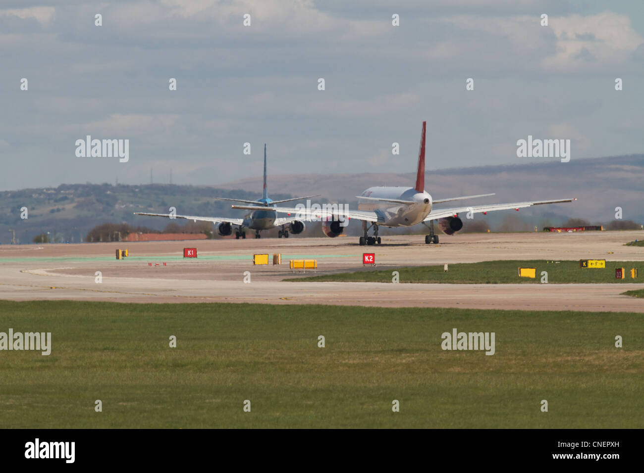 Deux avions à réaction à la piste de circulation au sol à l'aéroport de Manchester Banque D'Images