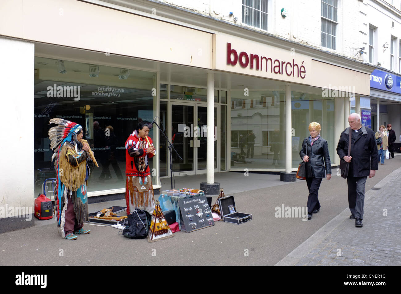 Les amuseurs publics d'Amérique du Sud et la vente de bijoux de la rue à l'extérieur d'un magasin fermé vers le bas en Falmouth, Cornwall Banque D'Images