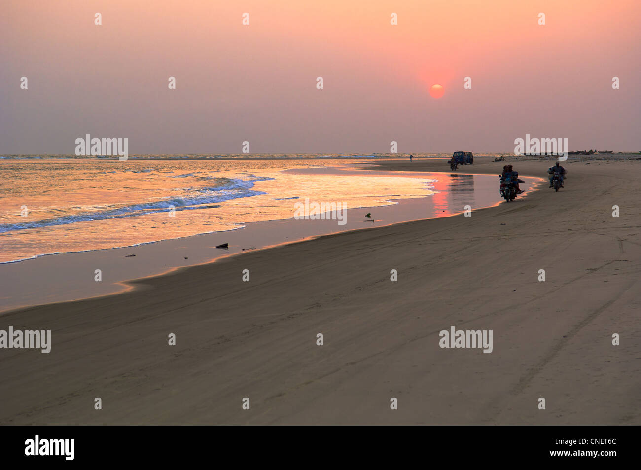 Les villageois motocyclettes au coucher du soleil le long d'une plage au Nigeria Banque D'Images