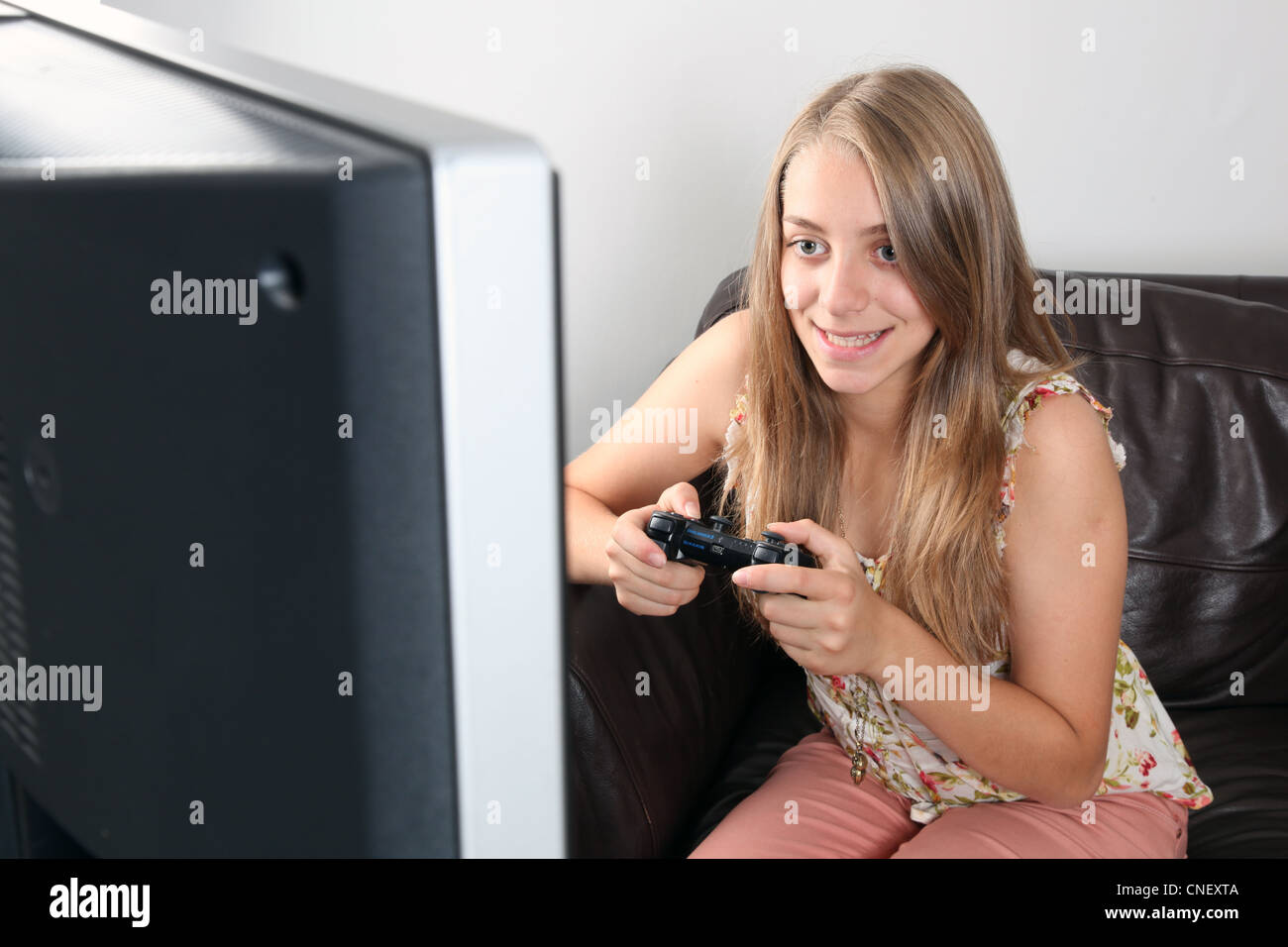 Jeune femme blonde tenant un contrôleur, tout en souriant (jeux playstation / x-box) jeu tv. Banque D'Images