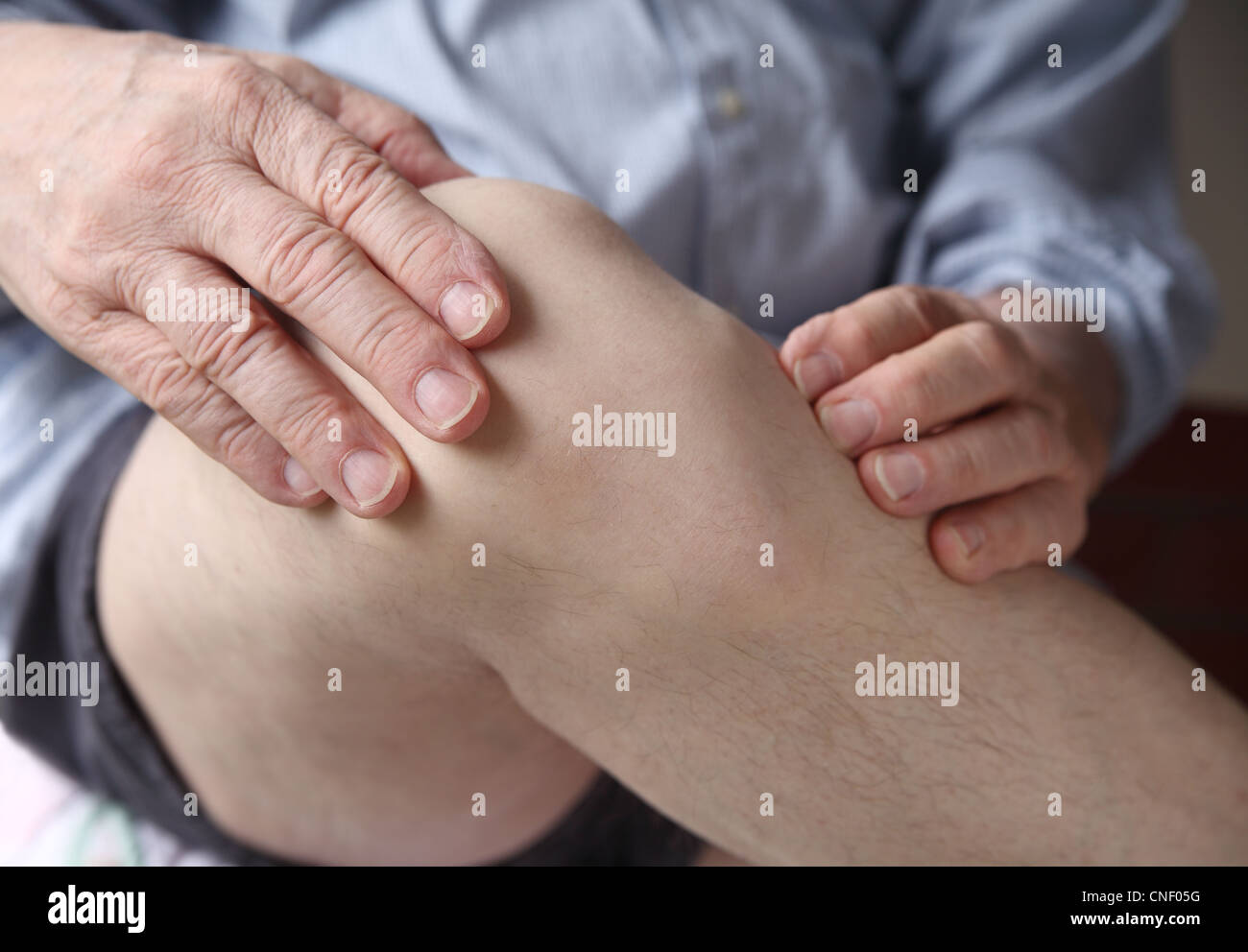 L'homme avec ses mains sur un genou douloureux Banque D'Images