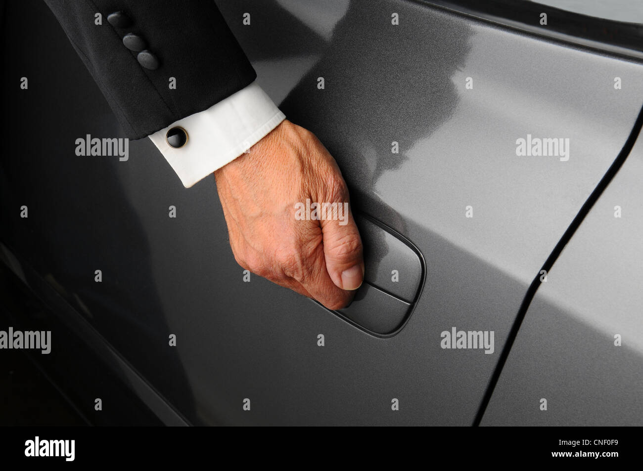 Un gros plan du mans part sur le loquet d'une porte de la voiture. Personne porte un smoking. Banque D'Images