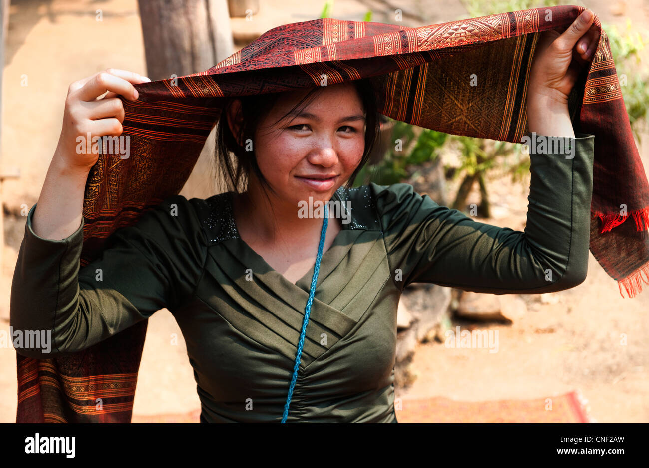 Jeune femme d'un village près du fleuve Mékong au Laos à l'aide de tissu produit localement à l'abri du soleil Banque D'Images