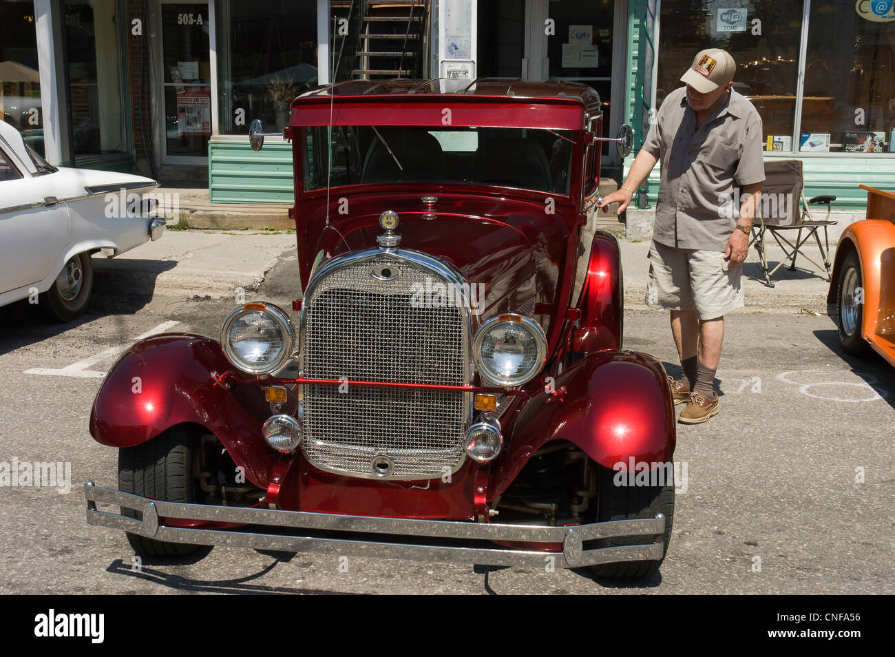 American Vintage 1930 rouge brillant et renouvelé de voiture avec des Polonais à côté de la voiture à une foire qui a eu lieu sur la rue main Banque D'Images