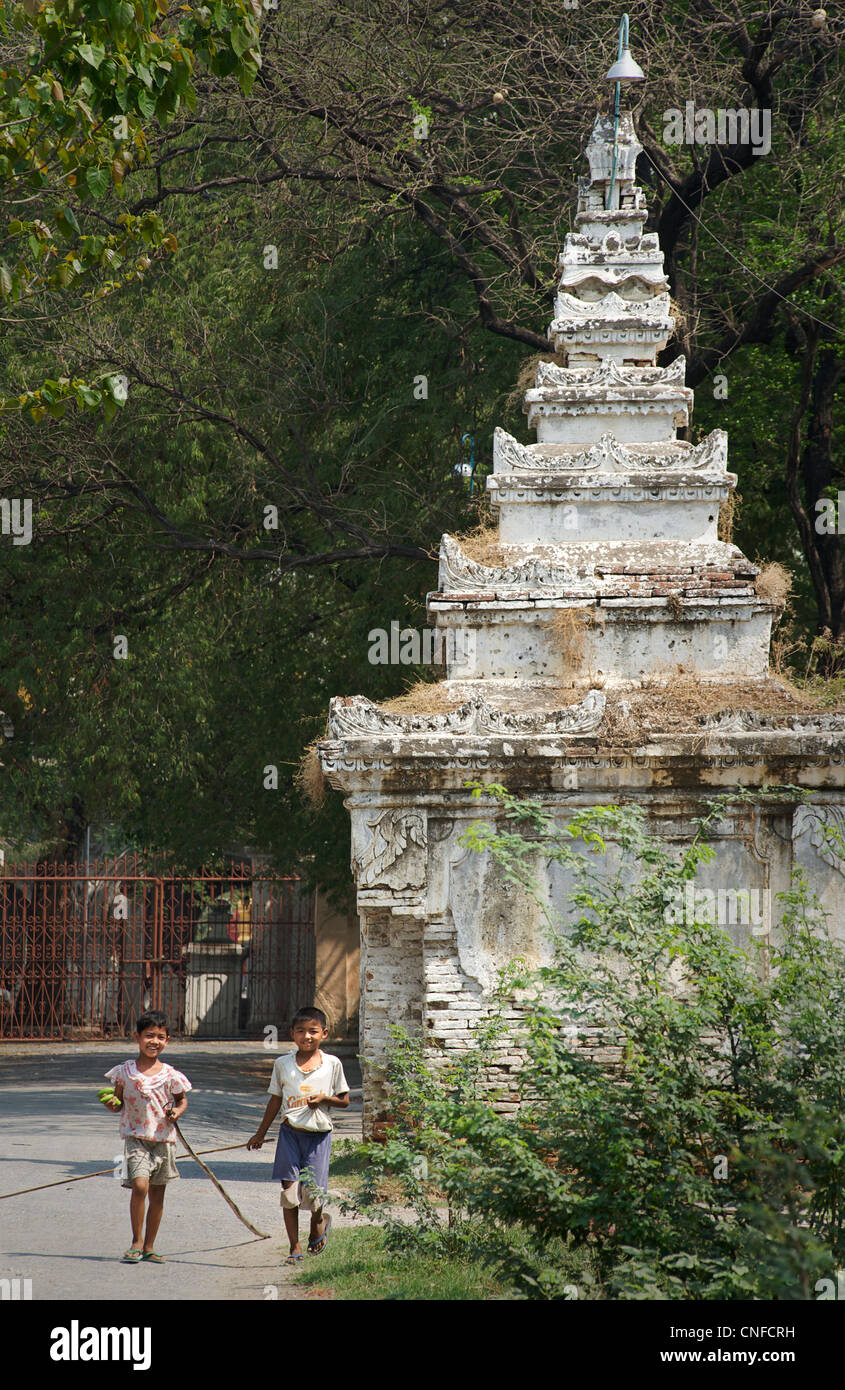 Les enfants birmans la collecte des fruits provenant d'arbres avec de longs bâtons. Mandalay, Birmanie. Myanmar Banque D'Images