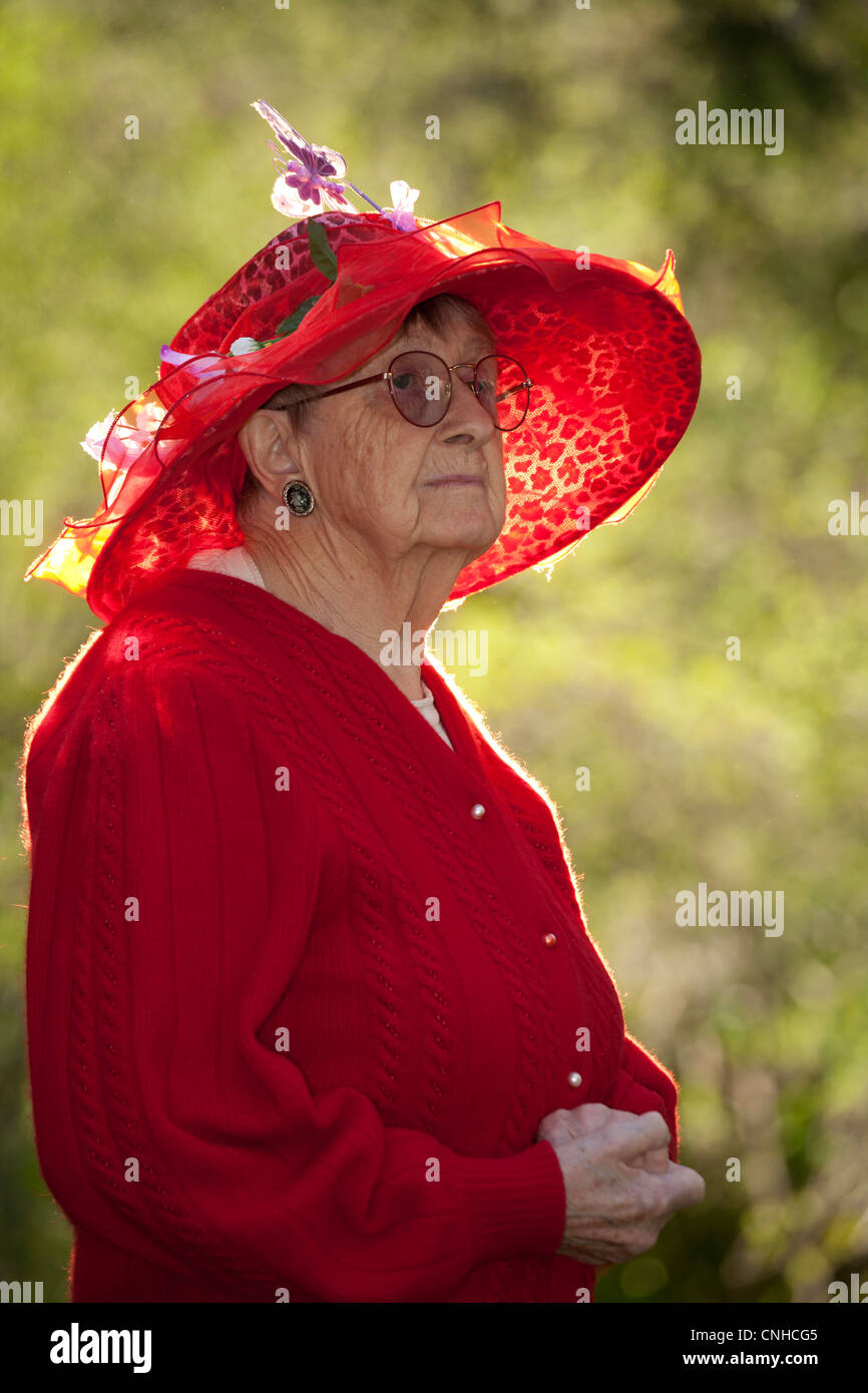 Citoyen Senior woman wearing red Easter bonnet hat-Victoria, Colombie-Britannique, Canada. Banque D'Images