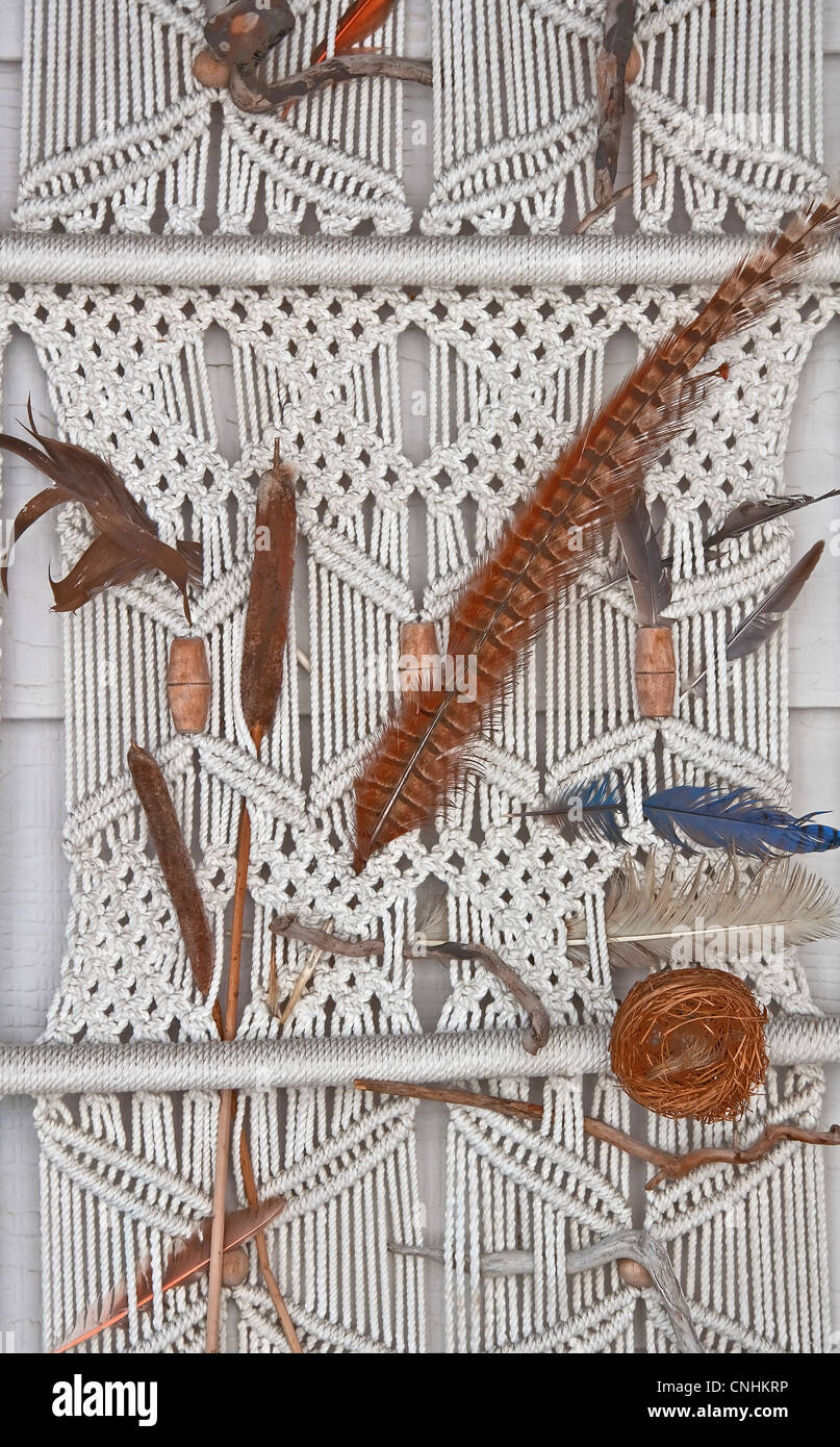 Partie d'un blanc avec des cordes faites de macramé dans un wall hanging, de plumes et d'autres éléments naturels ajoutés pour compléter. Banque D'Images