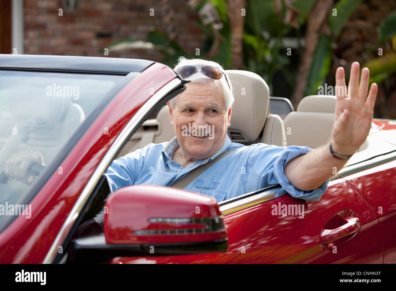 A senior man waving from convertible de siège conducteur Banque D'Images