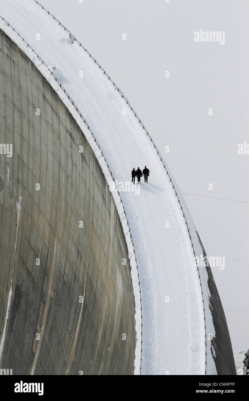 Trois personnes marchant au-dessus du barrage Zervreila, Suisse Banque D'Images