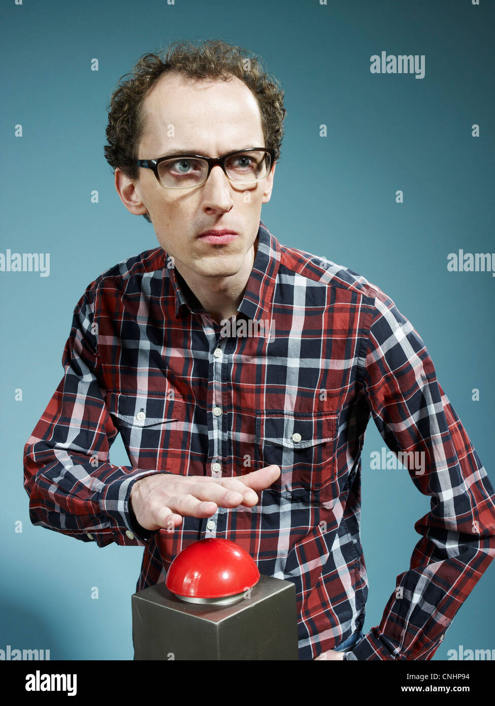Un nerdy guy avec sa main sur le point rouge au-dessus d'un game show buzzer Banque D'Images