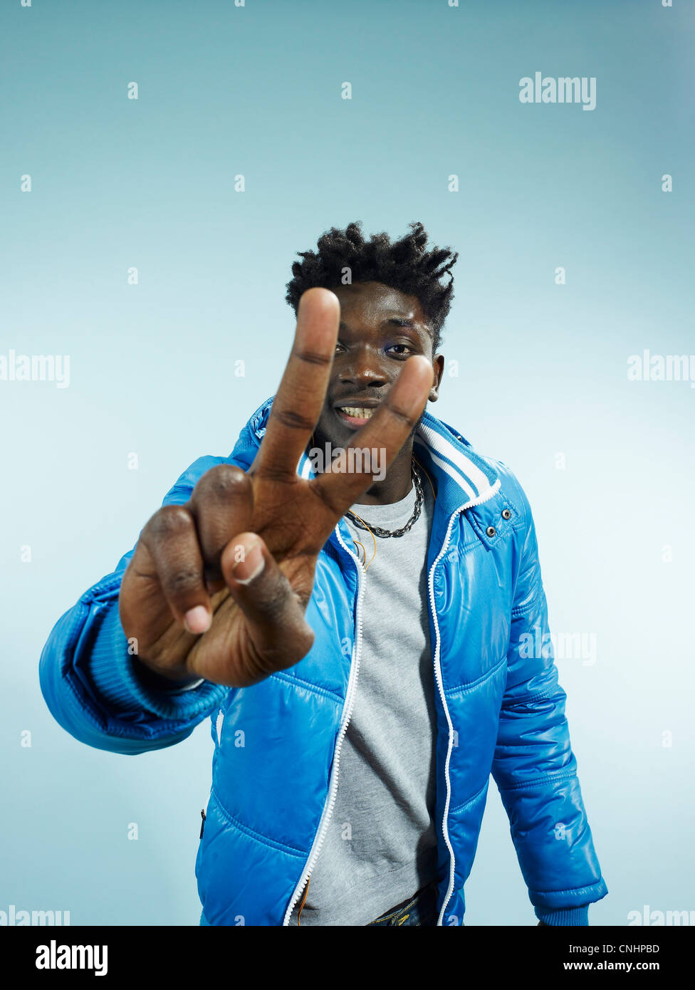 Un jeune homme de la hanche de clignoter le signe de la paix, focus on hand Banque D'Images