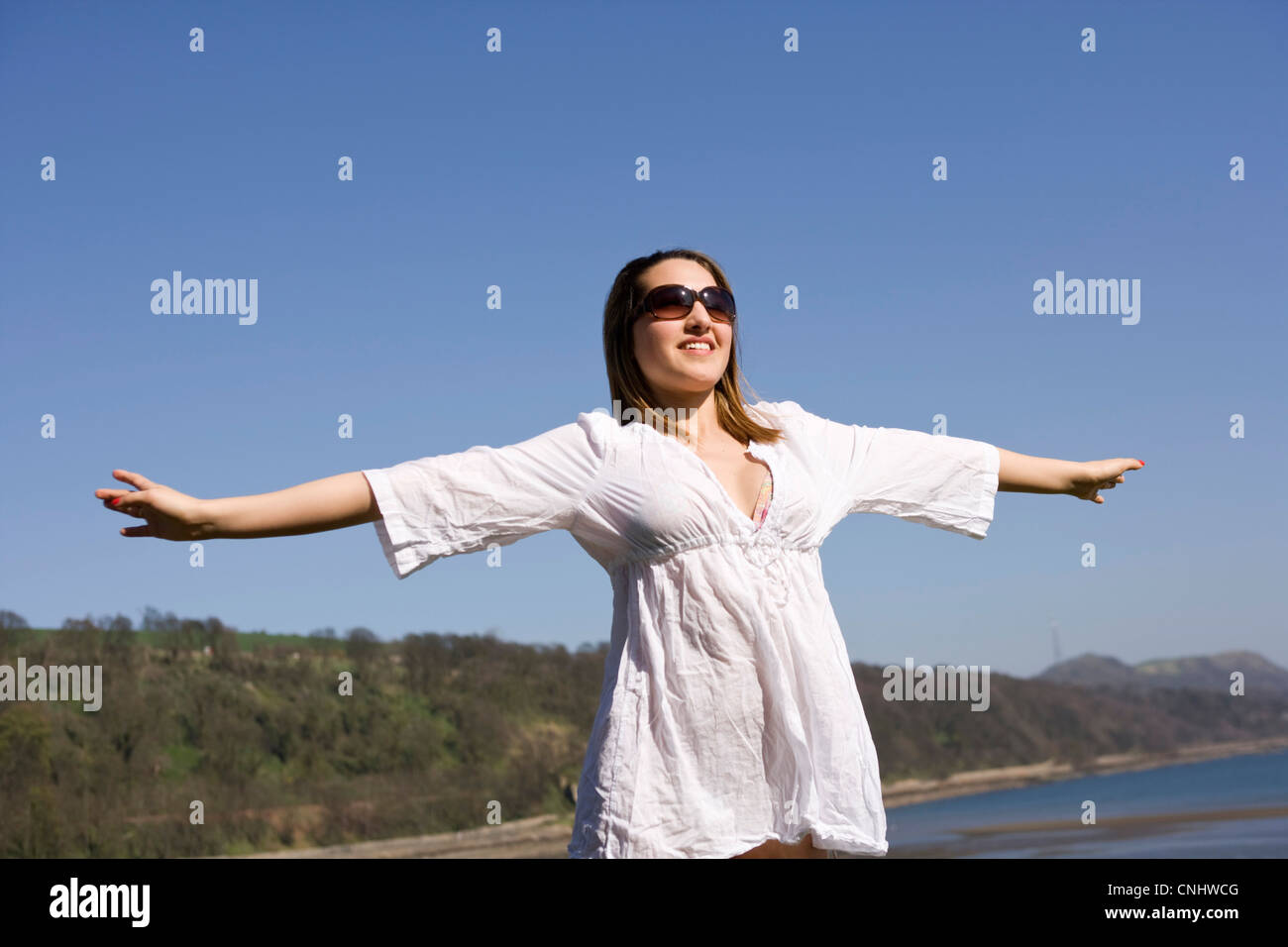 Jeune femme avec son bras tendu en profitant du soleil. Banque D'Images