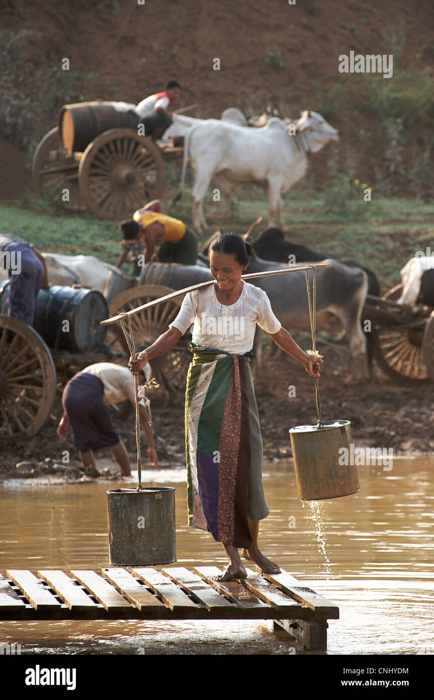 Femme birmane la collecte de l'eau d'un réservoir situé entre le mont Popa et Bagan Birmanie. Le Myanmar. Les préparatifs du Festival de l'eau Banque D'Images
