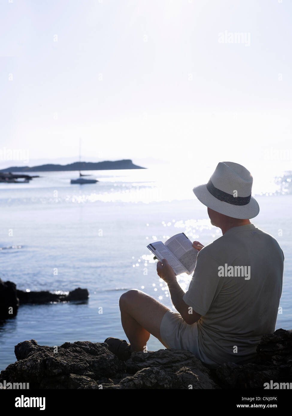 Man reading book par l'océan, Dubrovnik, Croatie Banque D'Images