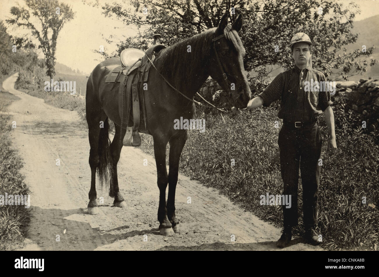 Jeune homme menant son cheval vers le bas une route de terre de Pays Banque D'Images