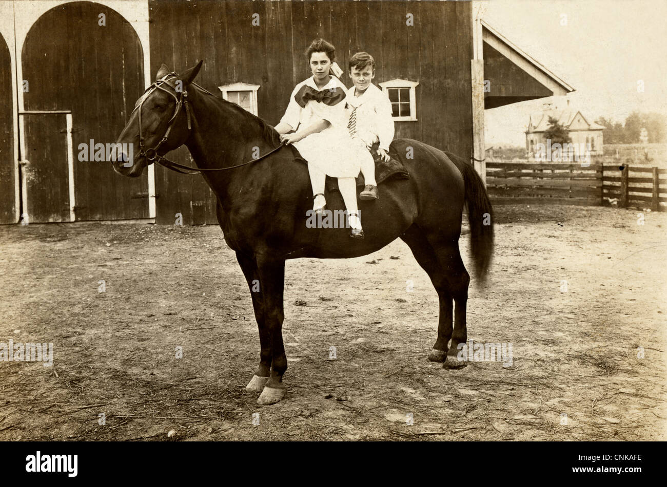 Petit frère et grande Sœur équitation un seul cheval à Barn Banque D'Images