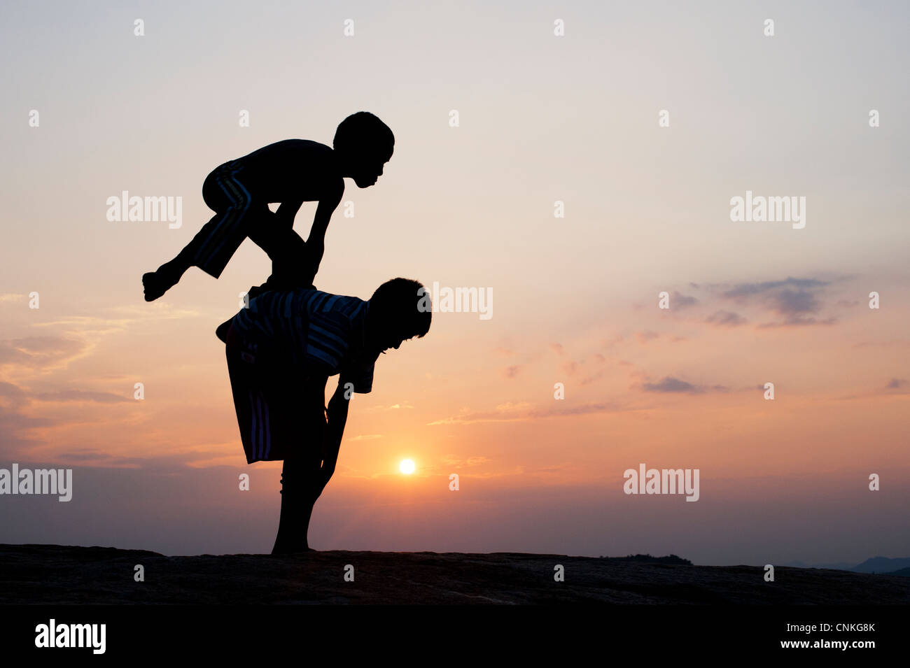 Silhouette de jeune Indien des garçons jouent à leap frog contre au coucher du soleil. L'Inde Banque D'Images