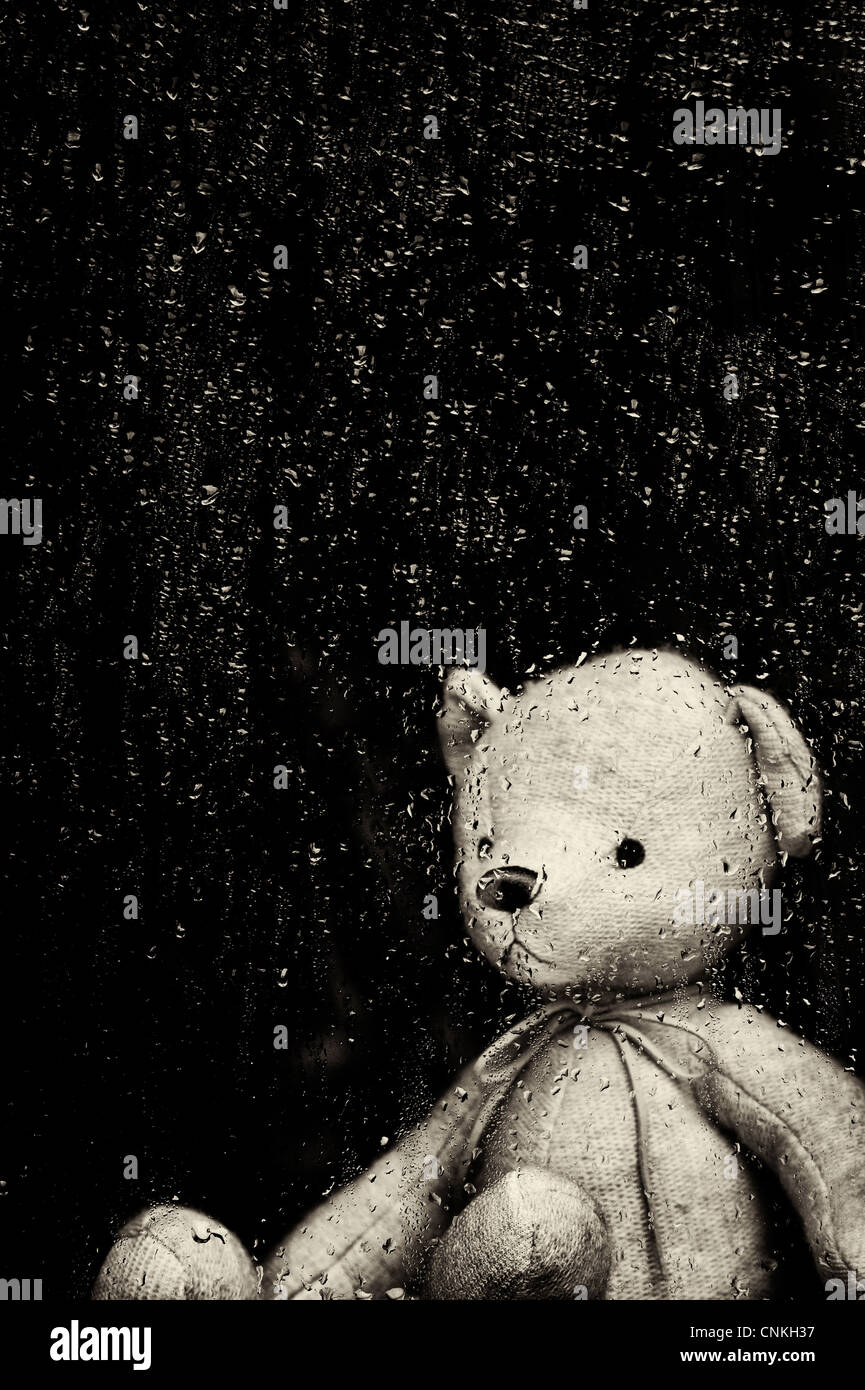 Triste ours à travers une fenêtre couverte de gouttes de pluie. Sépia. Still Life Banque D'Images