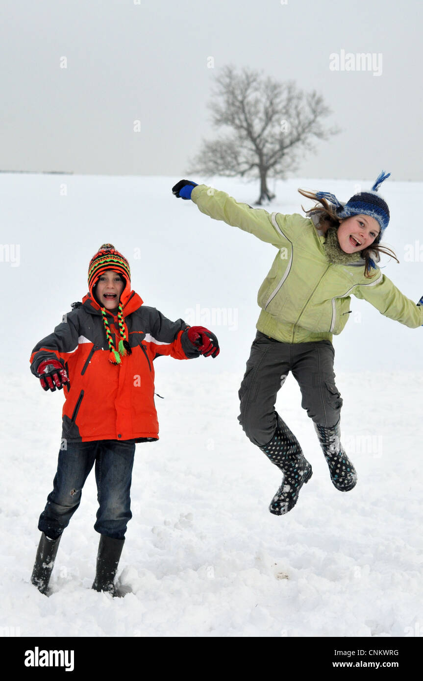 Les enfants sauter de joie dans la neige, avoir un jour de congé scolaire. Banque D'Images