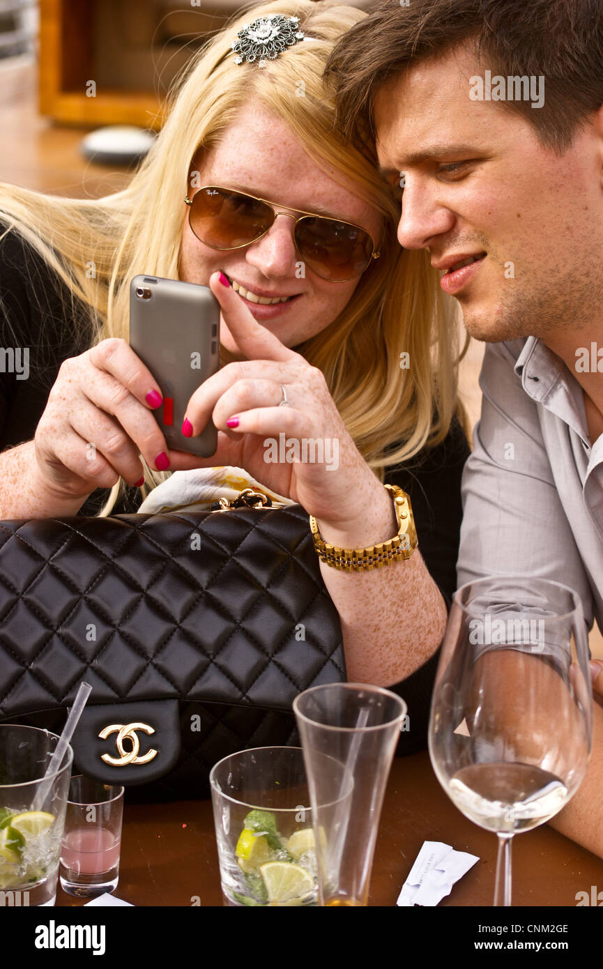 Un jeune couple à la recherche d'un smartphone à Park Hyatt Hotel, Dubai Creek, Dubai, Emirats Arabes Unis avec un sac à main Chanel Banque D'Images