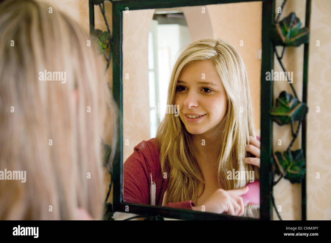 Fille de l'adolescence à brosser ses cheveux dans un miroir, UK Banque D'Images